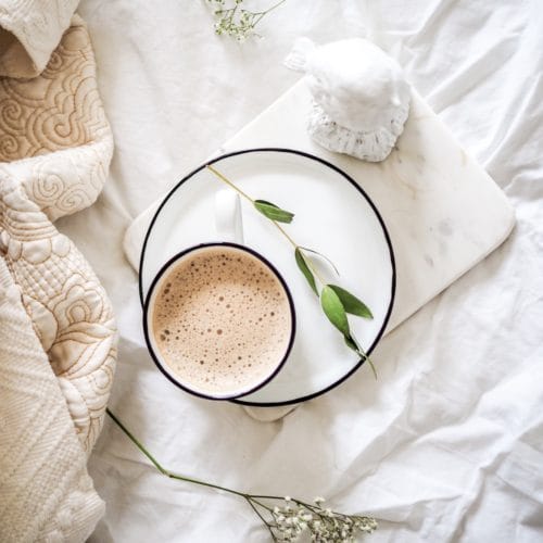 flatlay image of a cup of coffee on a bed