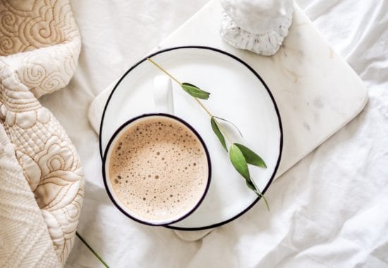 flatlay image of a cup of coffee on a bed