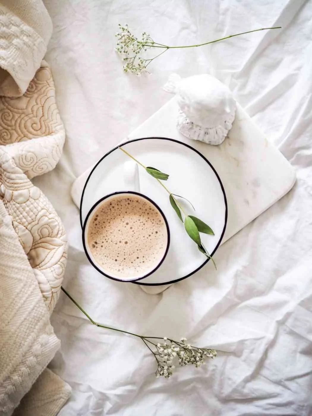 concept image for a mindful morning routine - flat-lay image of a cup of coffee on a bed