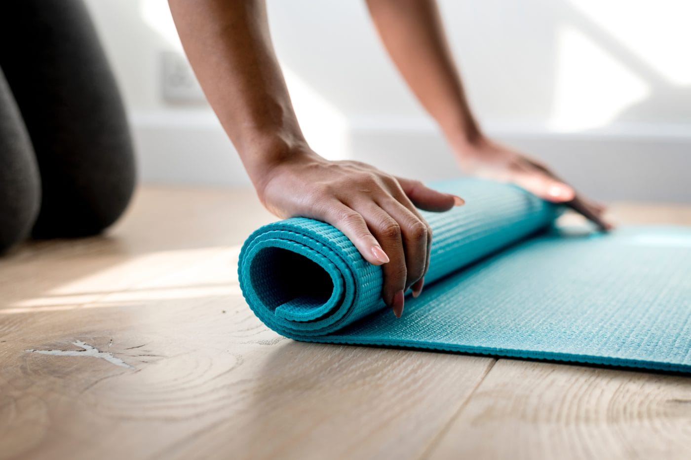 woman rolling her turquoise yoga mat
