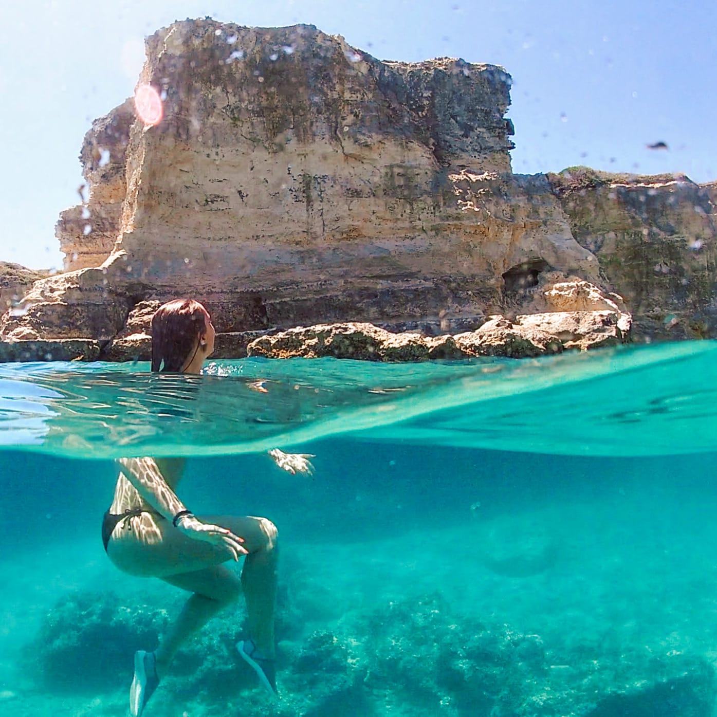 Half underwater shot of a woman swimming the waters of Torre Sant'Andrea in southern Puglia