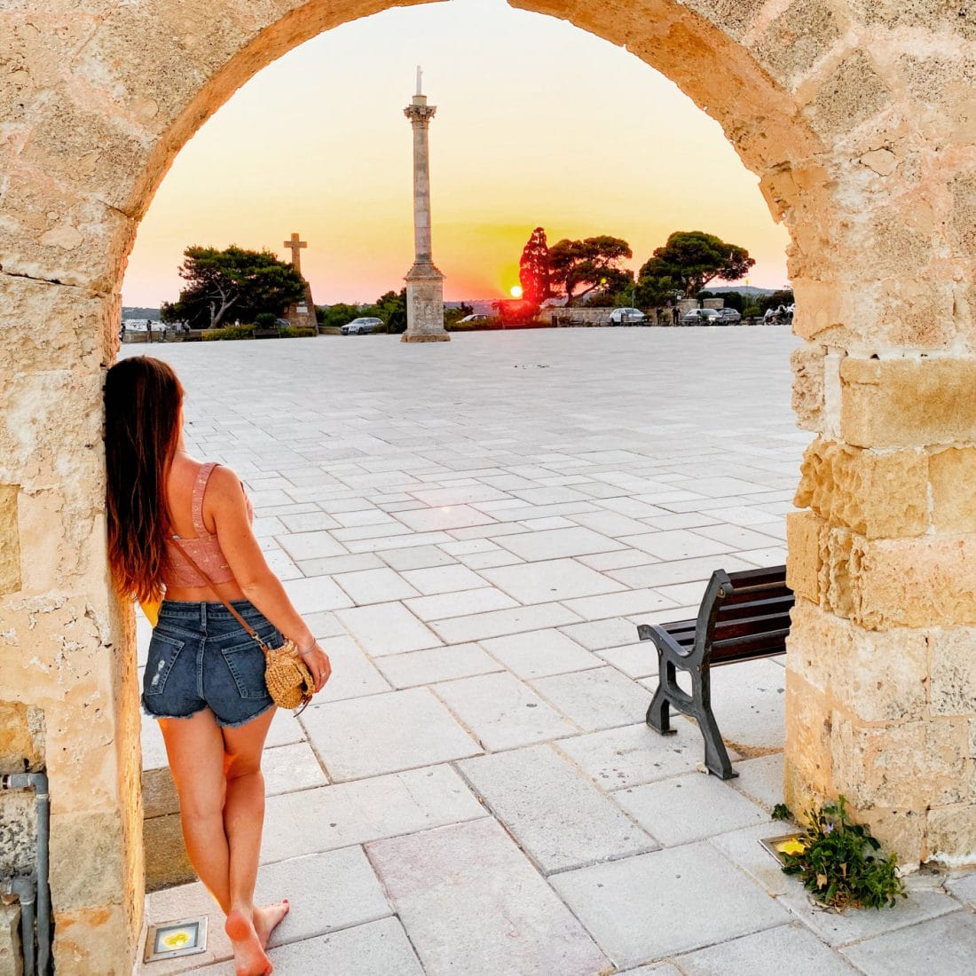 woman gazing at the sunset near the lighthouse at santa maria di leuca in puglia italy