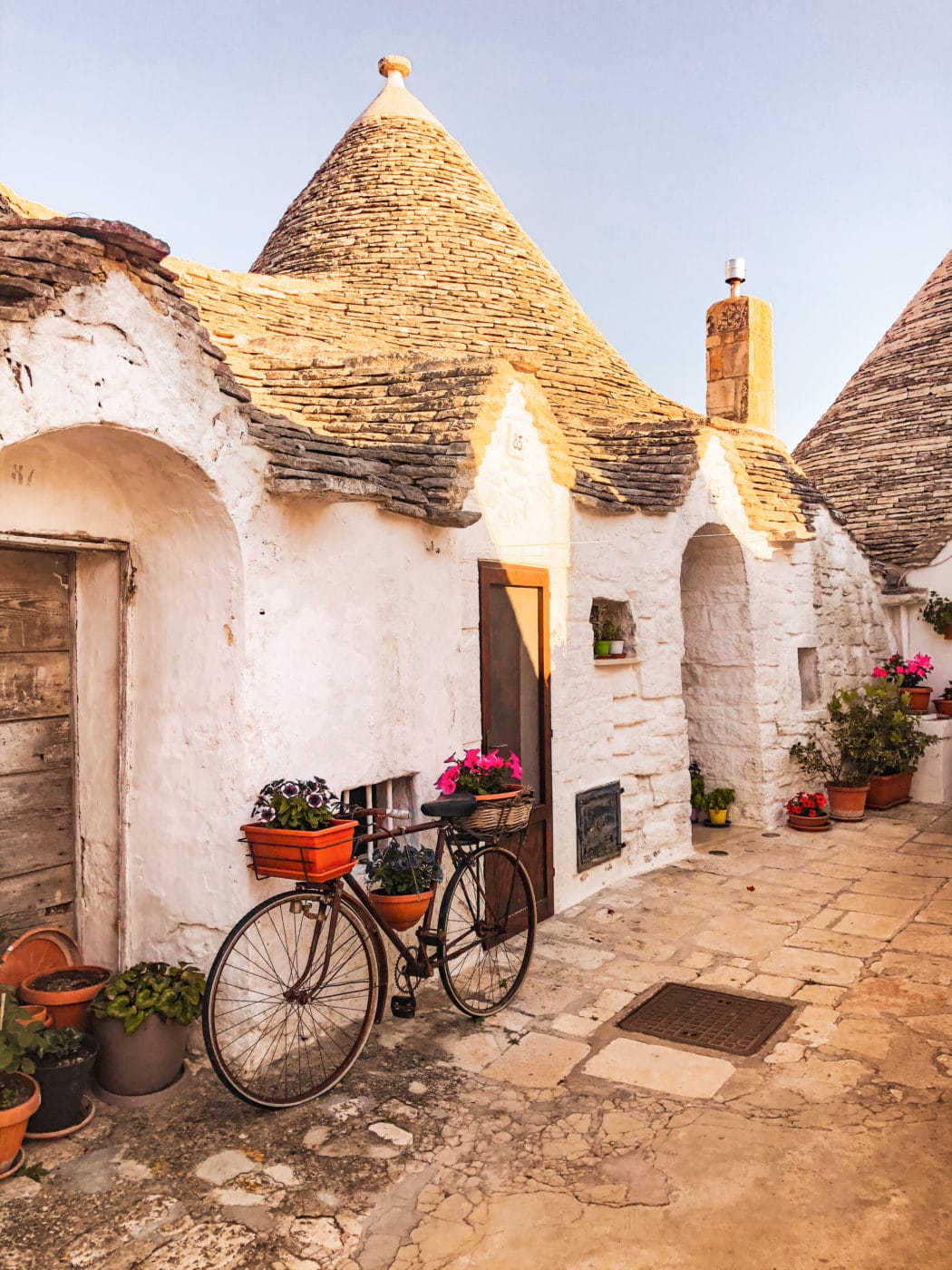 Cobblestoned alley with a view of a trullo and quaint little bike leaning on the side wall - Alberobello Puglia