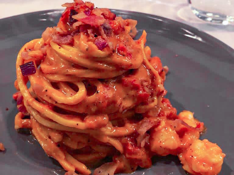 Amatriciana pasta with tomatoes cured pork and cheese very elegantly plated