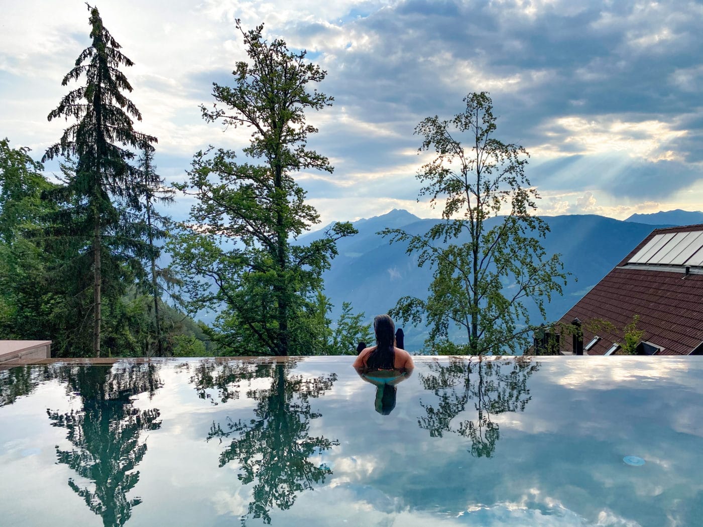 woman gazing out into the forest from an infinity pool at Miramonti Boutique Hotel, dolomites Italy