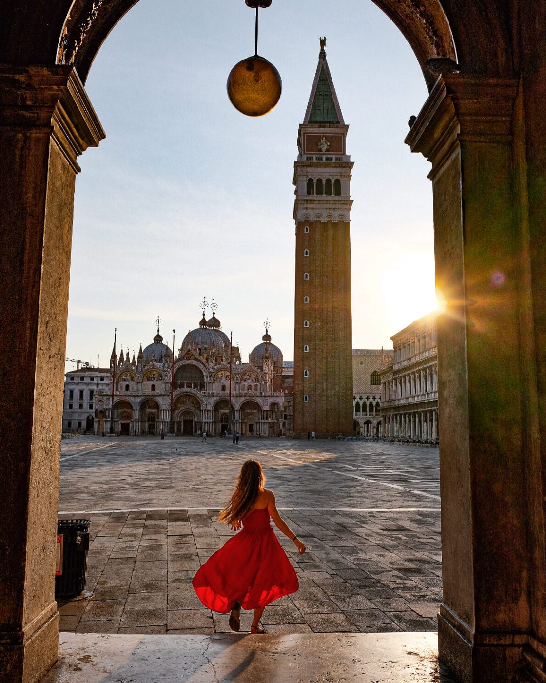Girl in red dress twirling about in Saint Mark's Square, Venice Italy at sunrise