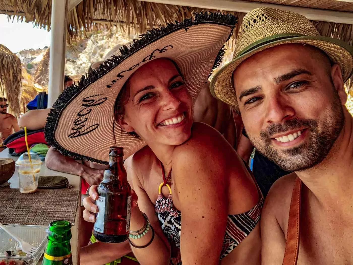 a couple smiling for the camera with straw hats at the beach