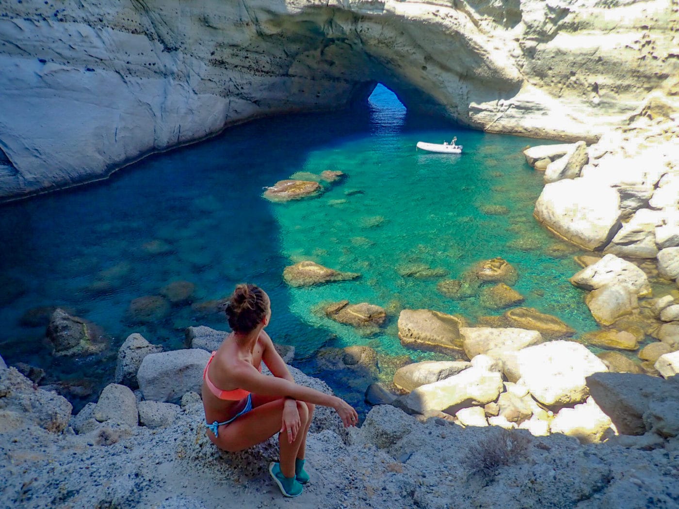woman gazing down into a secluded cove in milos Greece