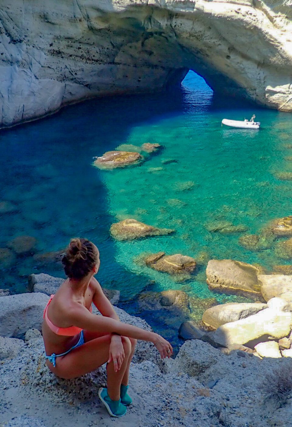 Woman looking out into a little secluded cove in Greece; island of Milos