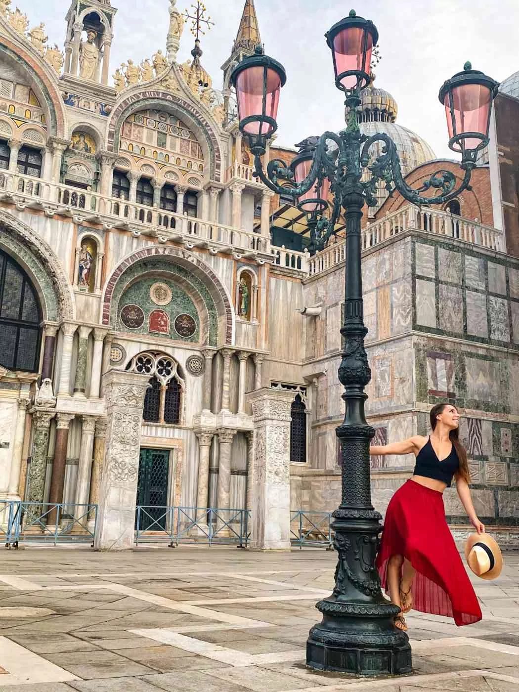 woman in red skirt twirling around lampost in saint mark's square venice, italy