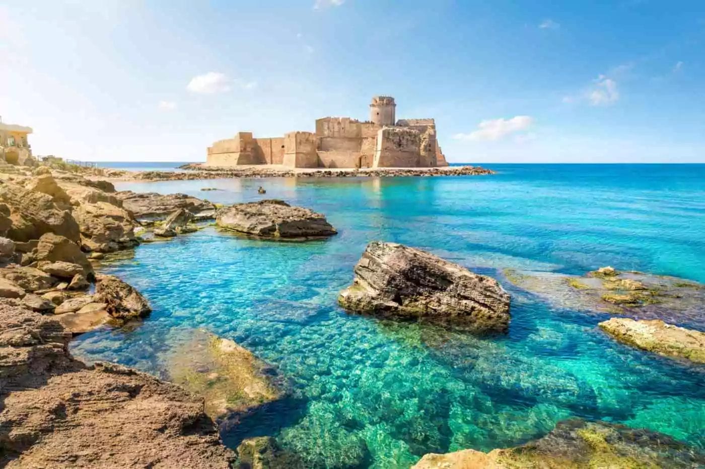 a peninsula with a beautiful castle surrounded by marvelous turquoise sea waters in Le Castella beach in Calabria, Italy