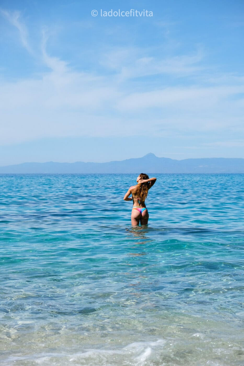 woman taking a dip in the turquoise waters of Marinella di Zambrone beach in Calabria Italy