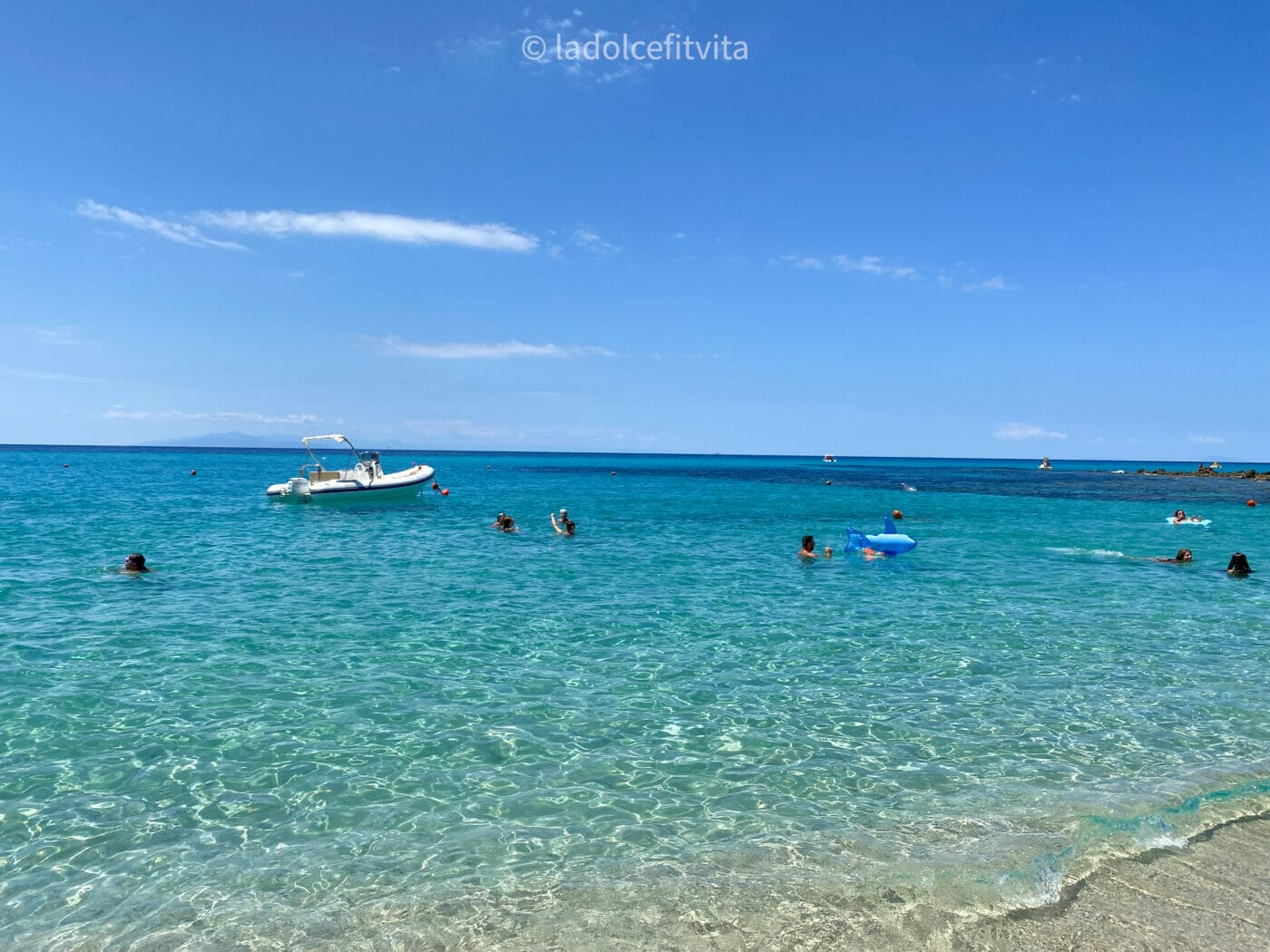 boat floating in stunning crystalline waters at a beach in Calabria Italy, Capo Vaticano Grotticelle beach