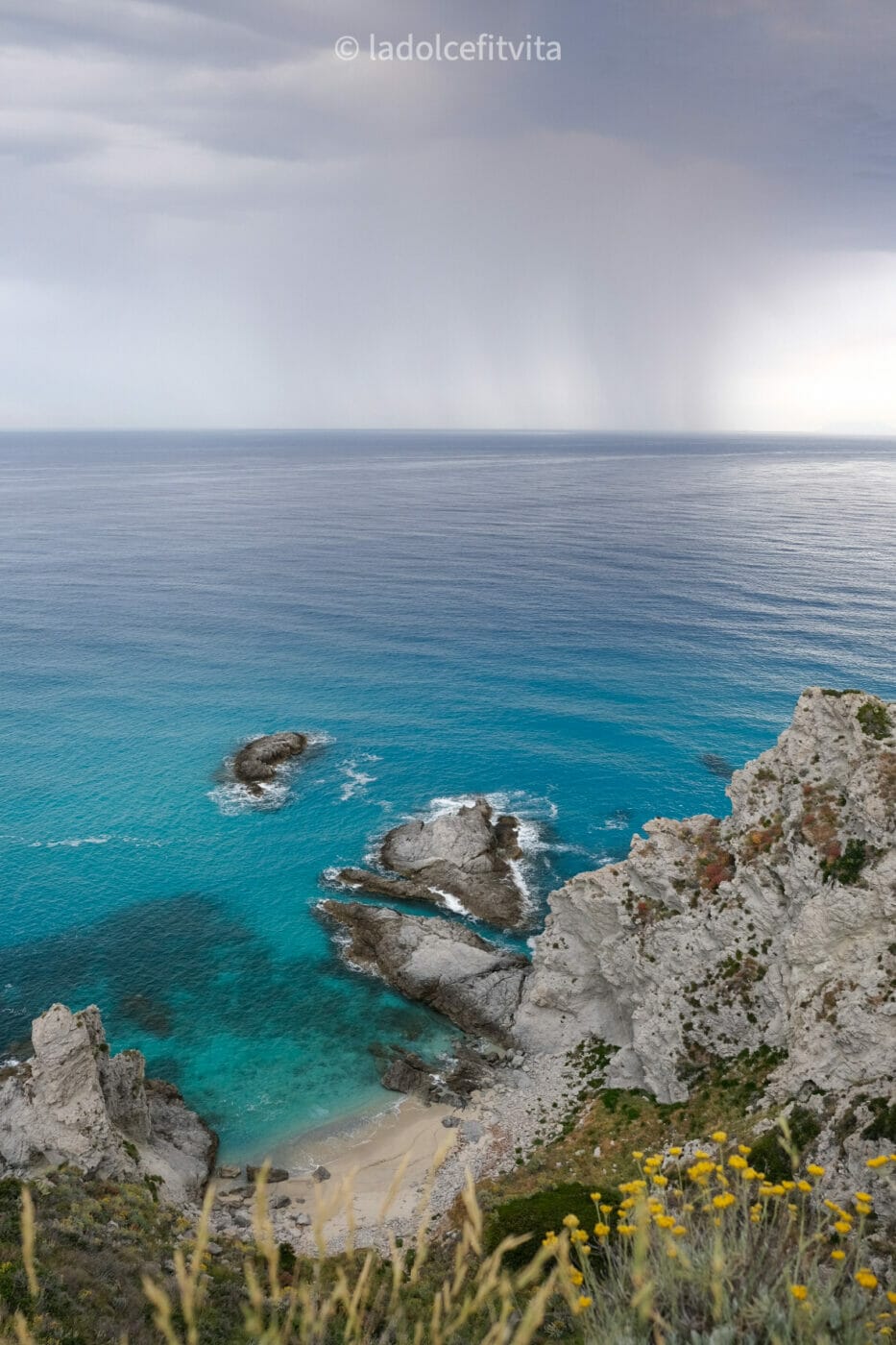 Bright turquoise waters contrasted with an ensuing storm in Capo Vaticano at Praia i Focu Beach in Calabria, Italy