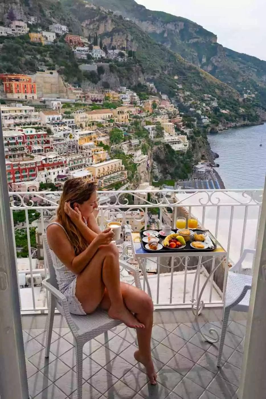 woman sipping coffee on a terrace overlooking the bay in Positano Italy
