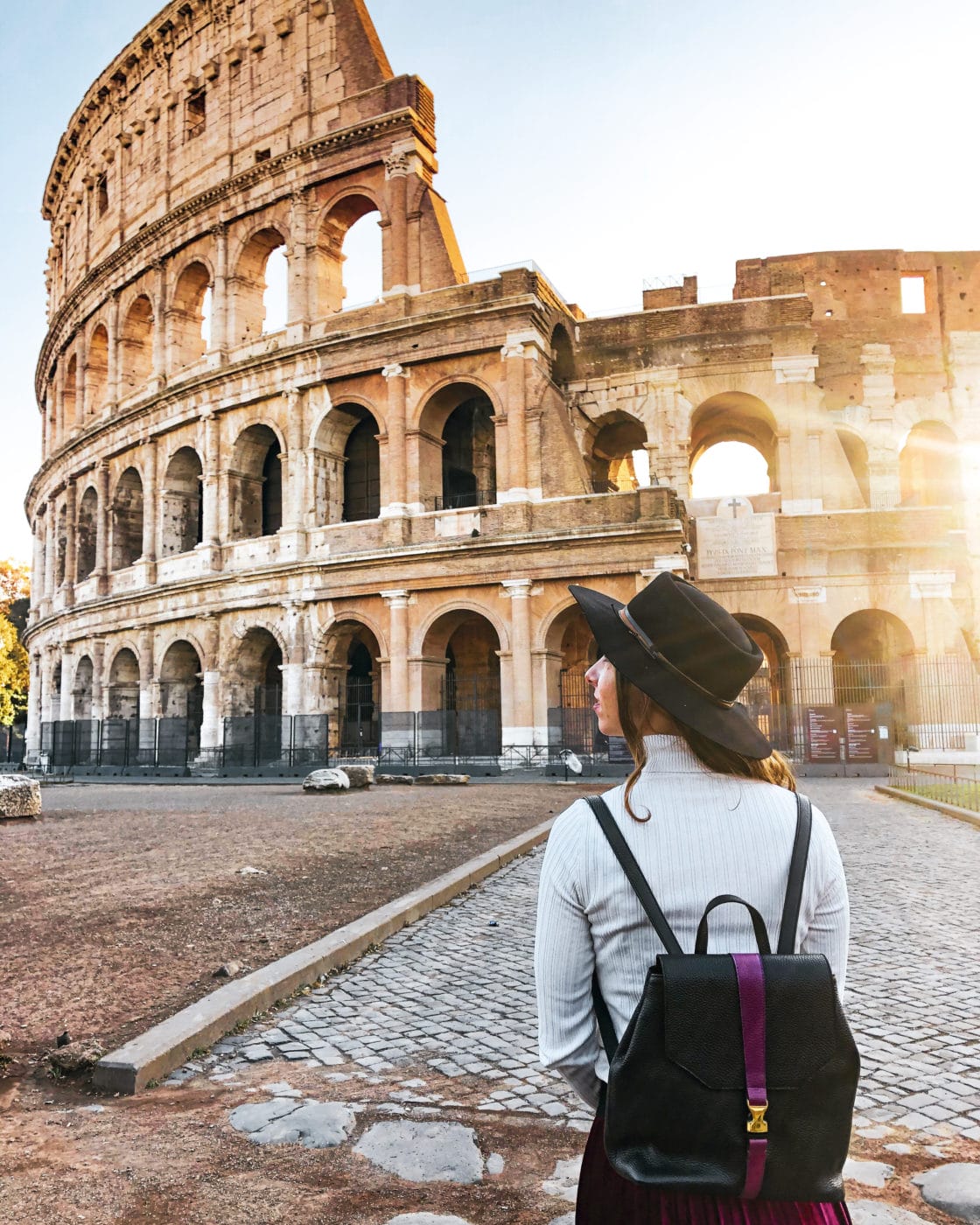 woman in hat with cute backpack exploring the colosseum in rome