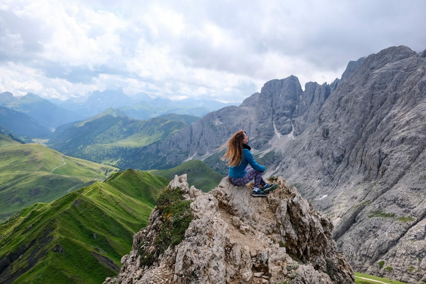 woman sitting on a mountain peak and gazing at the scenery below in the dolomites
