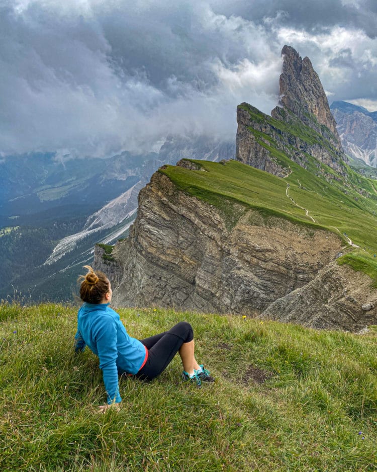woman gazing out at the jagged peaks of the seceda ridgeline mountain in the italian dolomites