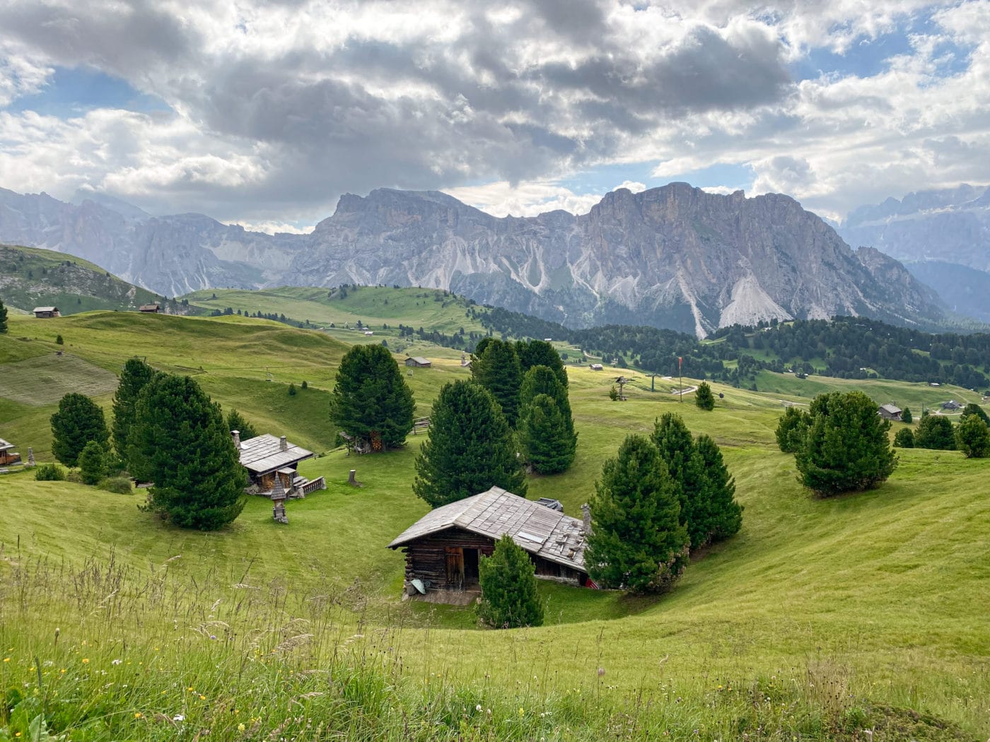 a cabin in a meadow with the dolomite mountains in the background