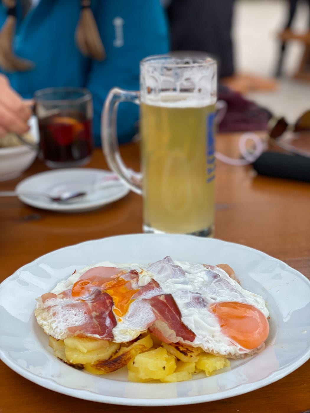 sunnyside-up eggs and potatoes with a radler beer as a typical lunch in south tyrol, italy