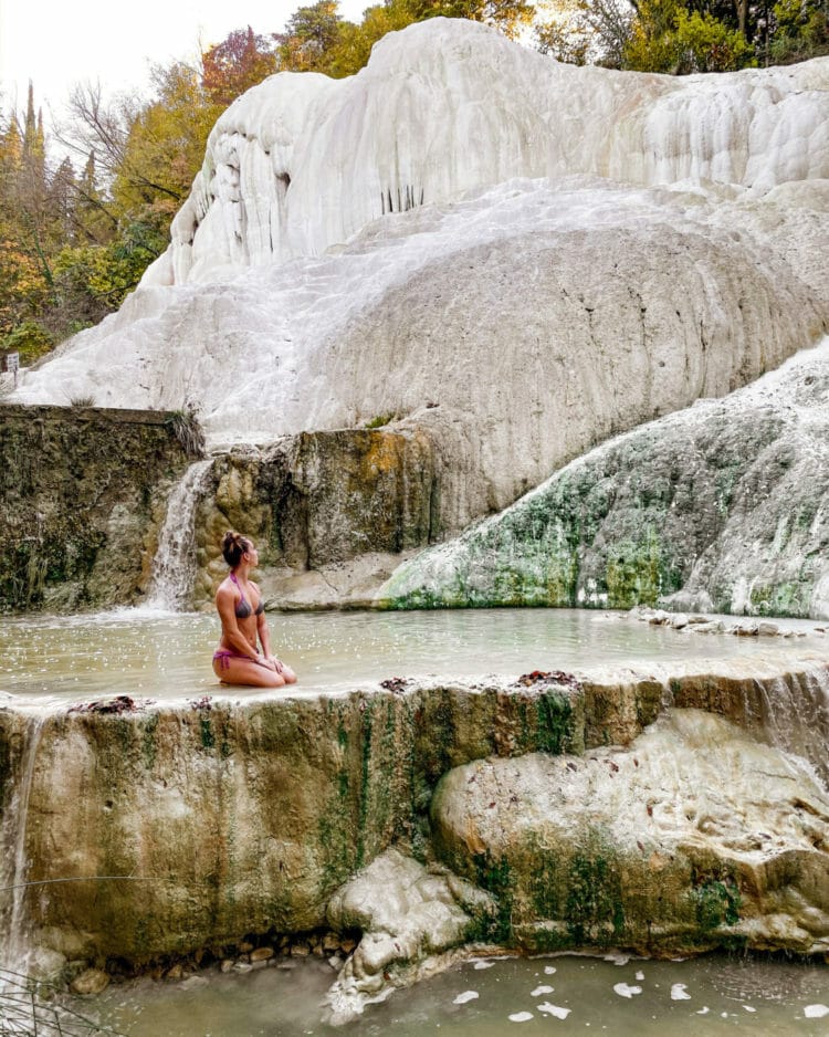 woman kneeling in the pools of bagni di san filippo hot springs