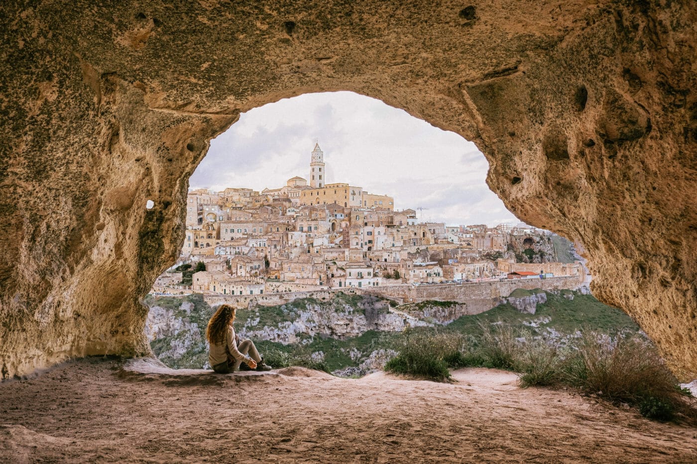 woman in a cave that overlooks the city of matera