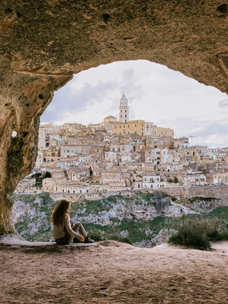 woman in a cave overlooking the sassi di matera in italy