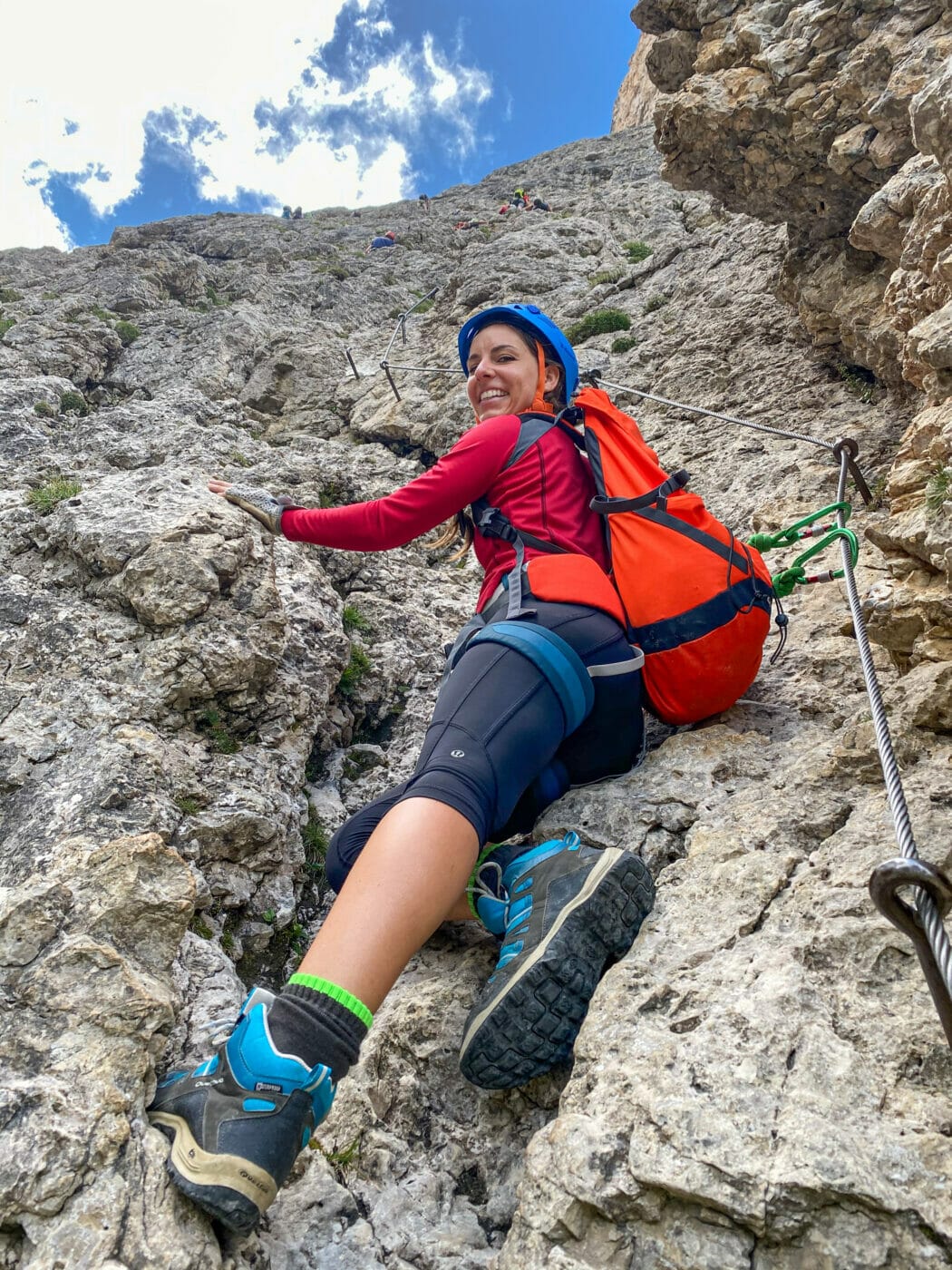 woman hiker resting against a rock as she ascends the strenuous via ferrata Tridentina in the Dolomites Italy