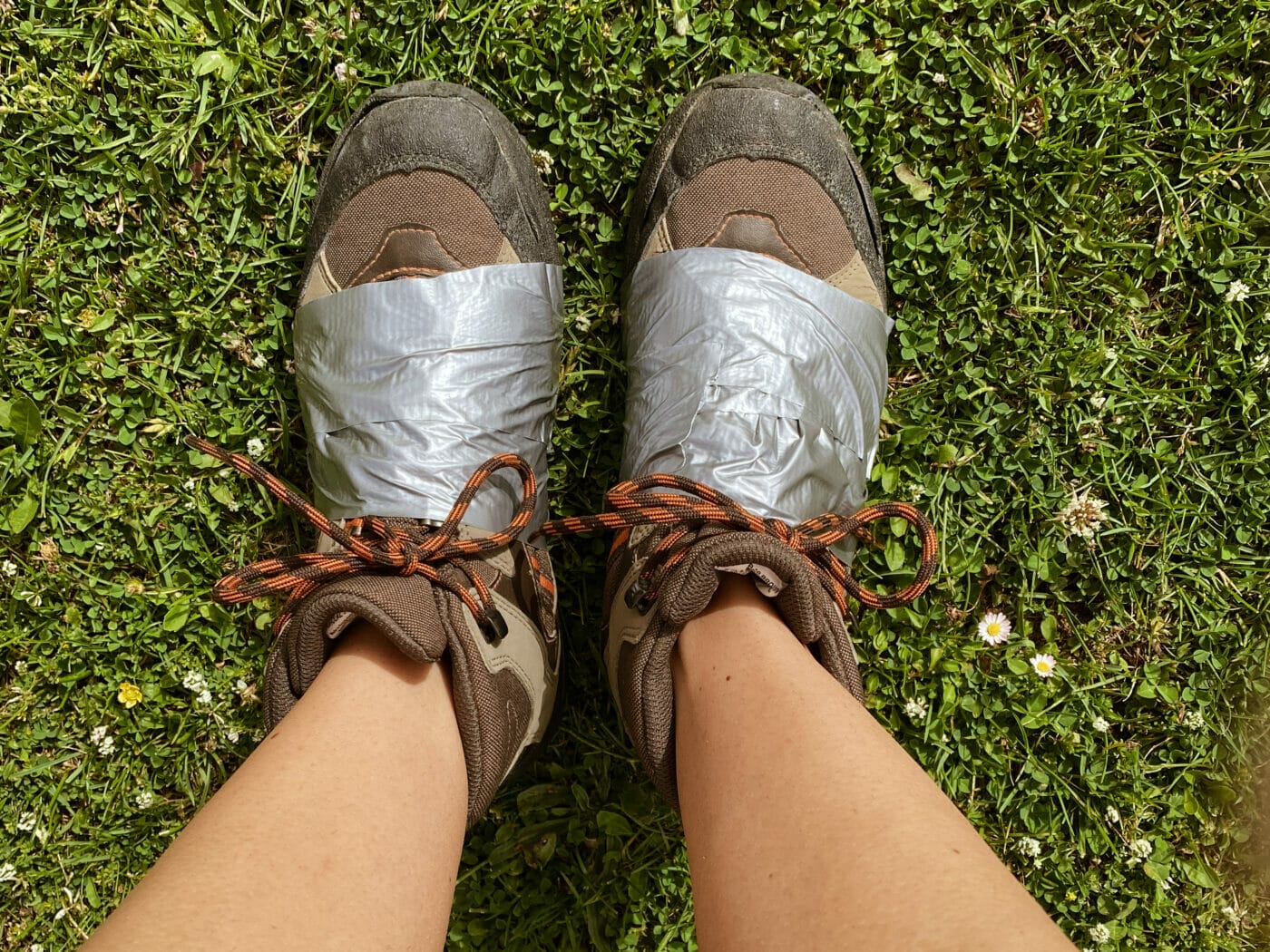 hiking shoes that have been duct tape to help keep them together since soles fell apart