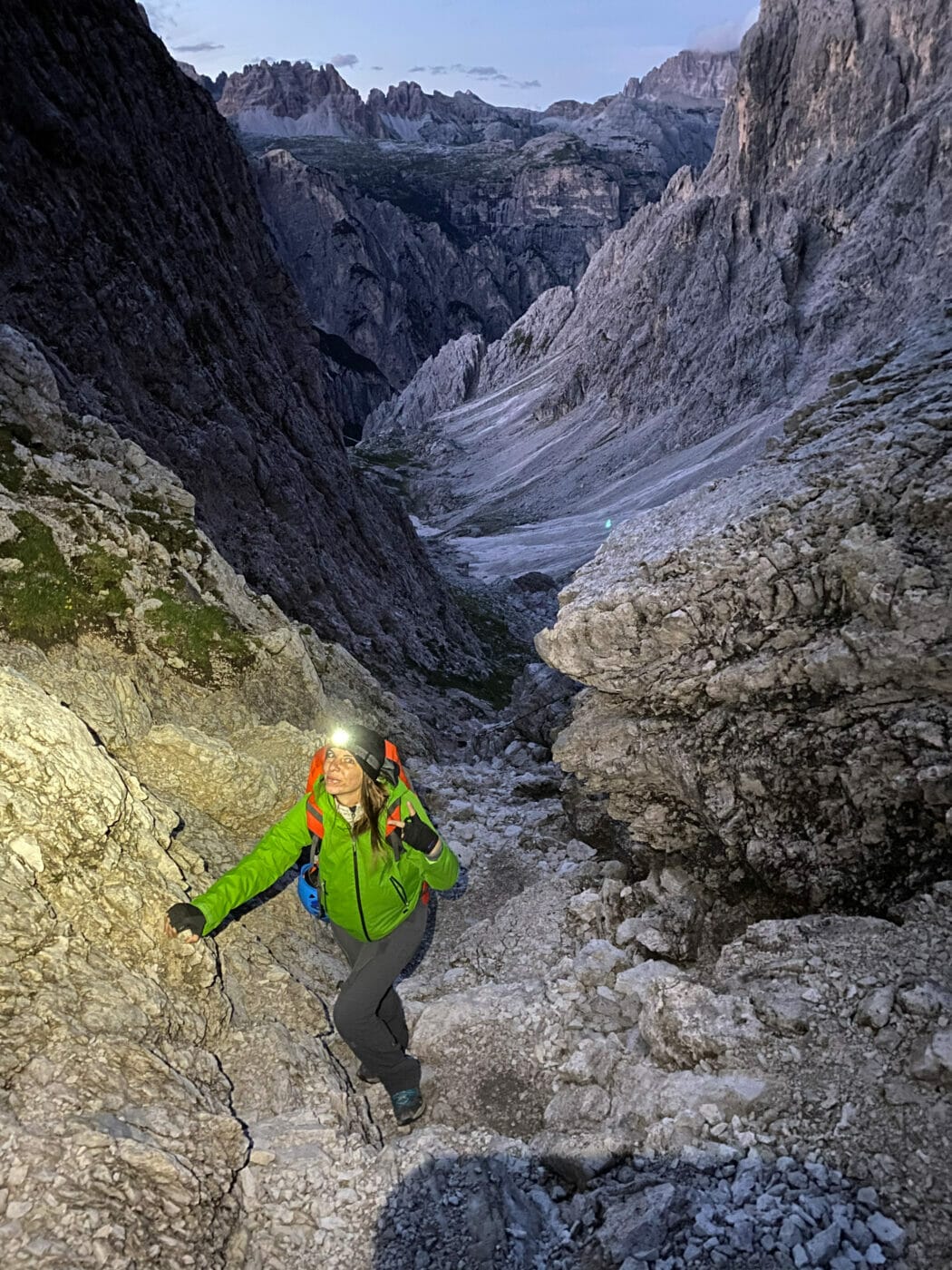 woman hiker with headlamp as she hikes at dusk in the Dolomites