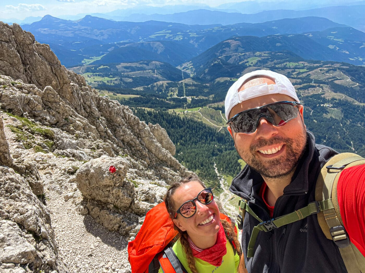 couple hiking in hiking gear with polarized glasses taking a selfie while trekking the dolomites