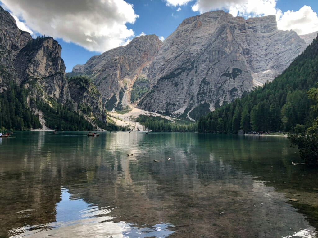 the still waters of alpine lake Lago di Braies with towering Croda del Becco mountain peak in the background