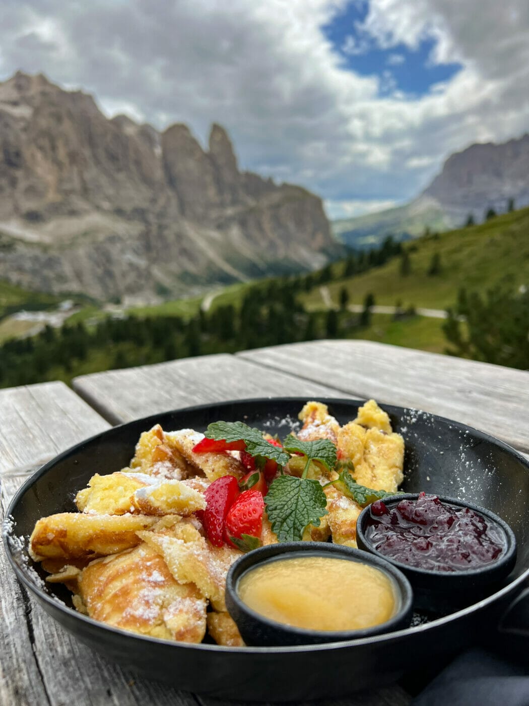 kaiserschmarren a frittata with jam on a rifugio table with the Sella group mountains in the background