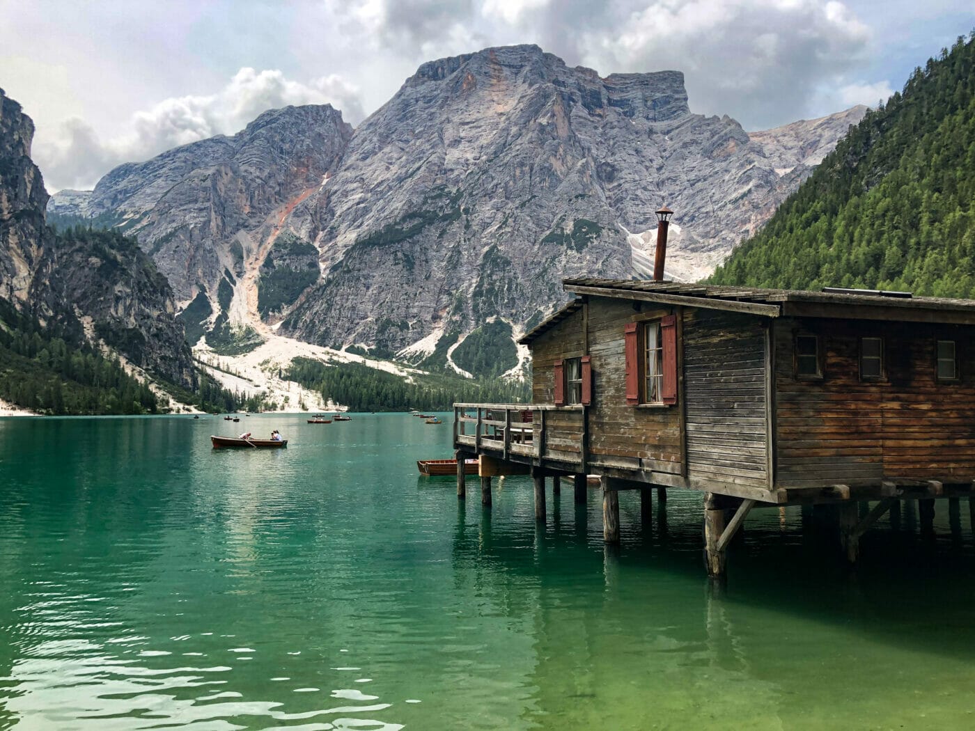 charming wooden boathouse at emerald alpine lake Lago di Braies with magnificent Dolomite mountains in background