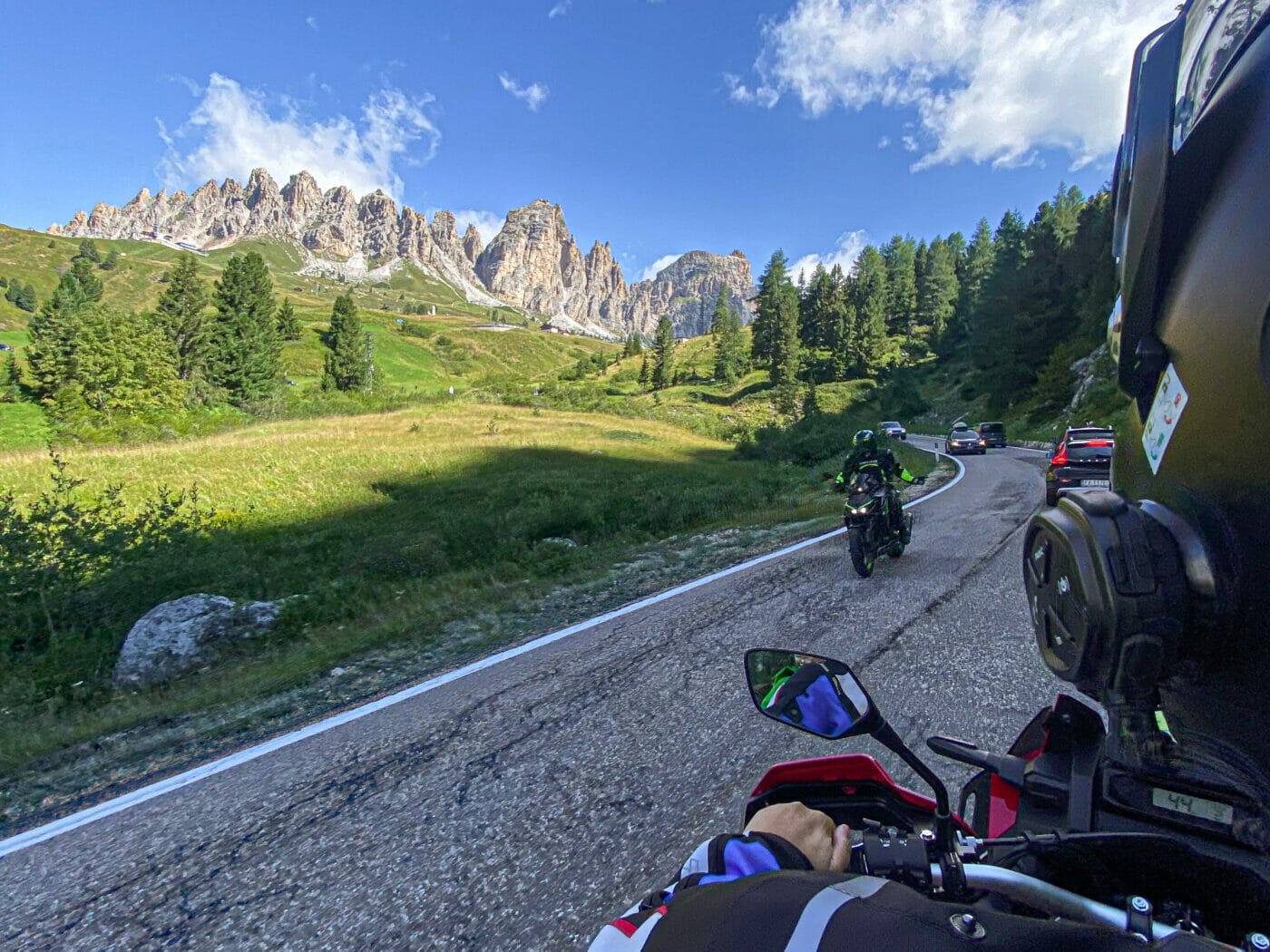 motorcyclist riding through passo gardena in the dolomites with meadow and mountains in the background
