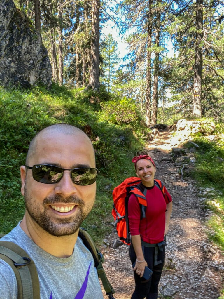 two hikers posing for a selfie on a gravel path in the Dolomites in Puez Odle Nature Park