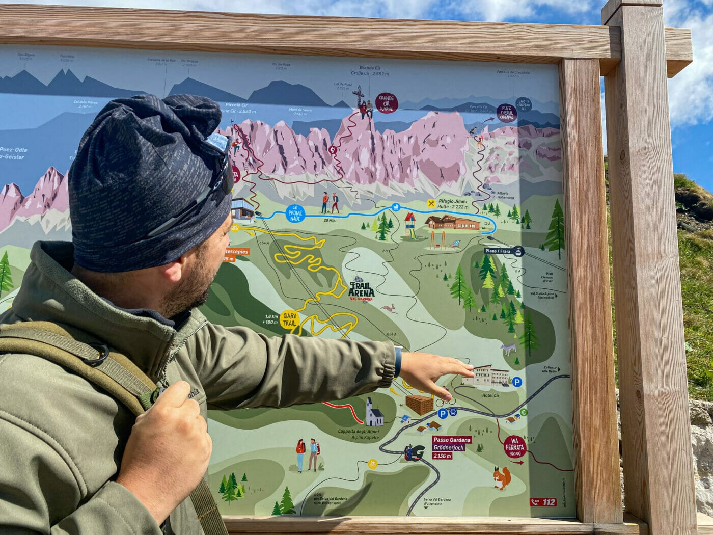 hiker pointing and explaining a map of the dolomites area in passo gardena