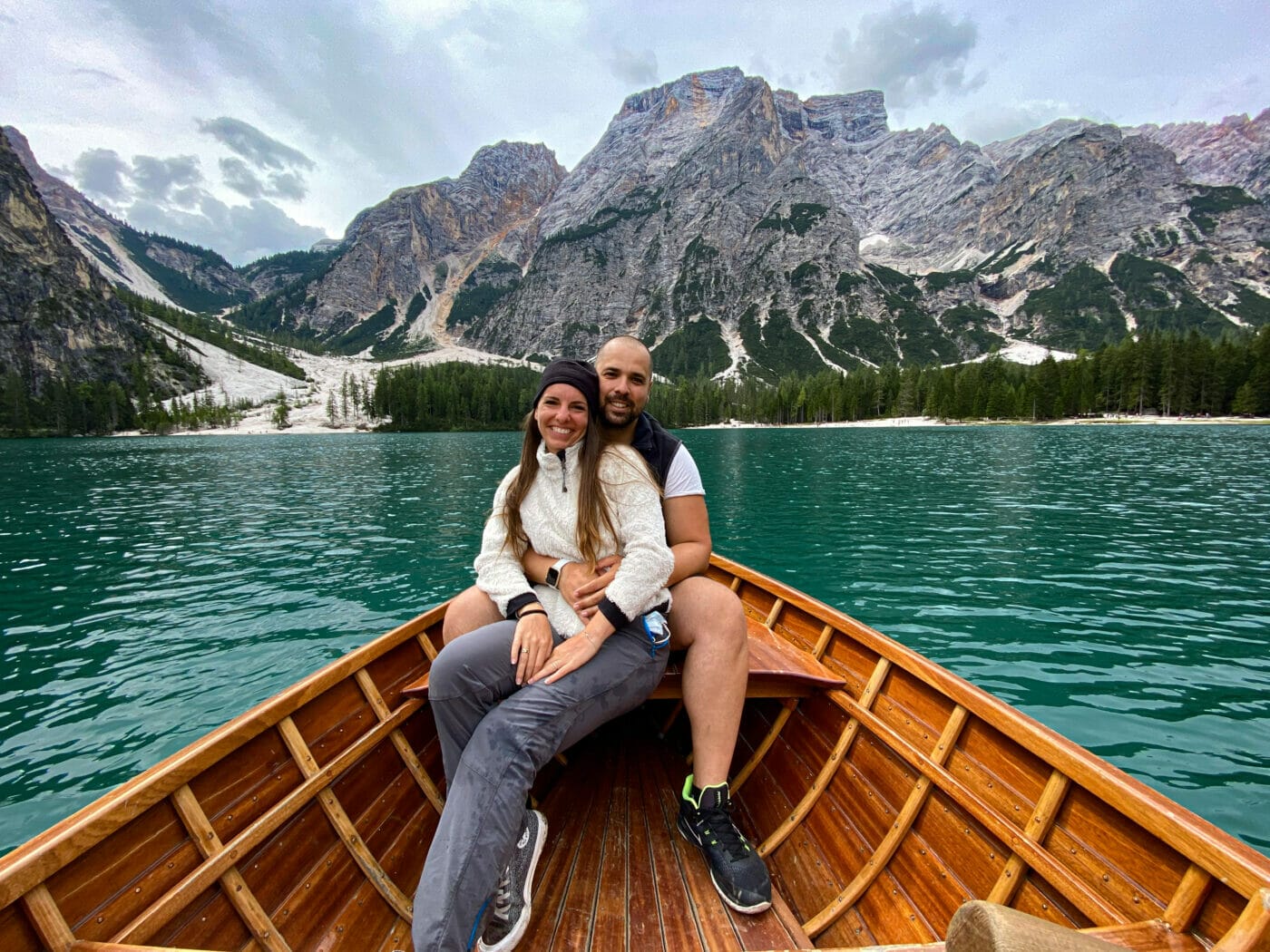 couple posing for a picture in a wooden rowboat in the middle of picturesque Lago di Braies in the Italian Dolomites