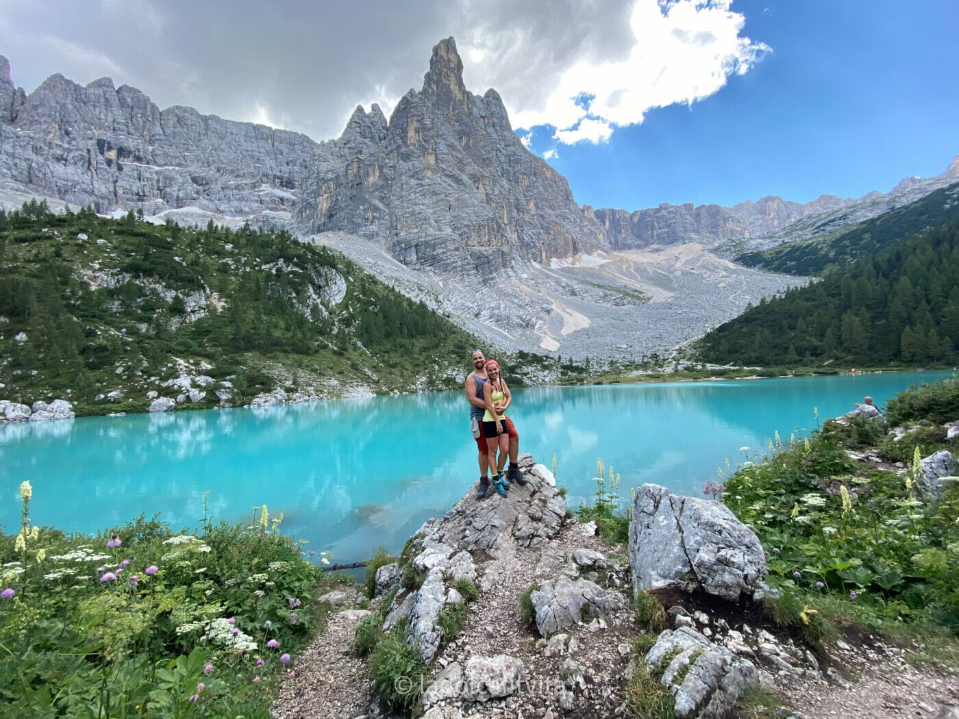 a couple standing for a picture perched on a rock on the banks of the sorapis lake in the Dolomites Italy