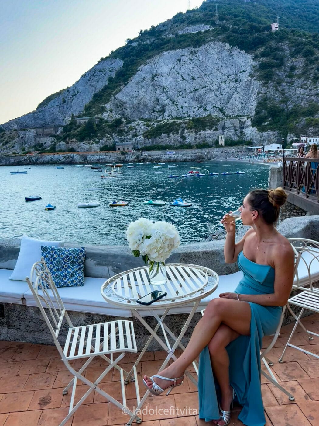 a woman enjoying a glass of champagne as she gazes out on the sea on the beautiful terrace of Torre La Cerniola on the Amalfi Coast in Italy