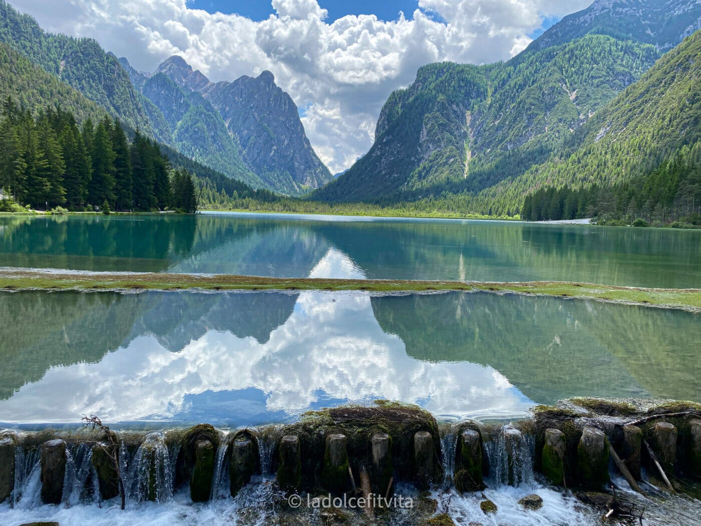 pristine crystalline waters at dobbiaco lake in italy with Dolomites mountains in the background