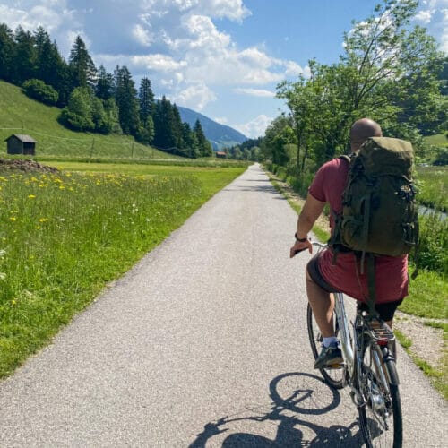 male cyclist on a bike trail in the dolomites with grass on both sides of the paved path