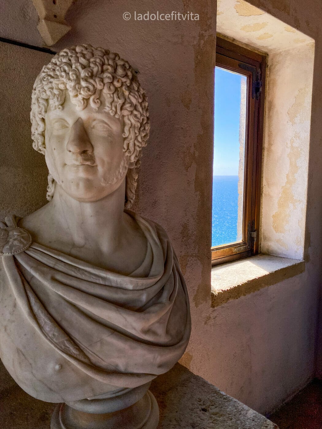 bust marble sculpture in front of a window that looks out on the Tyrrhenian sea in Calabria Italy