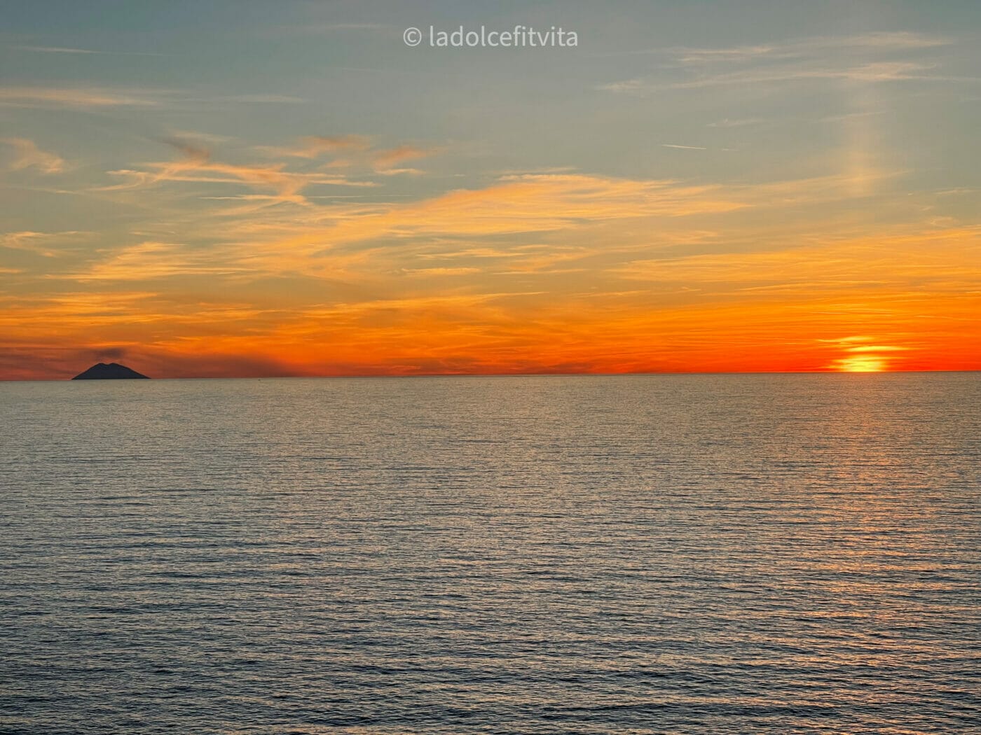 bright orange sunset with stromboli island on the horizon as seen from a terrace in Pizzo Italy