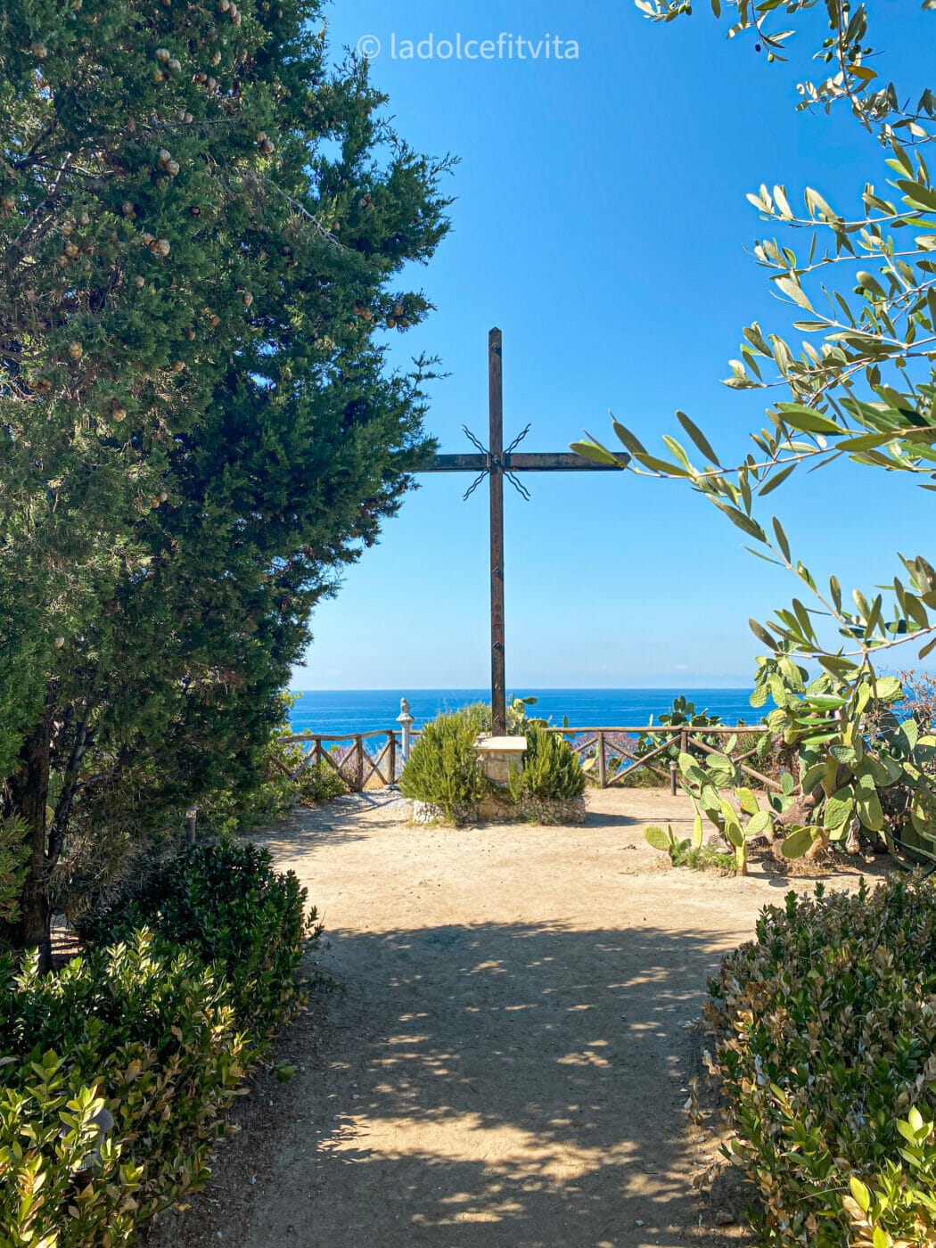 a cross in the gardens of the sanctuary of Tropea with the sea in the background