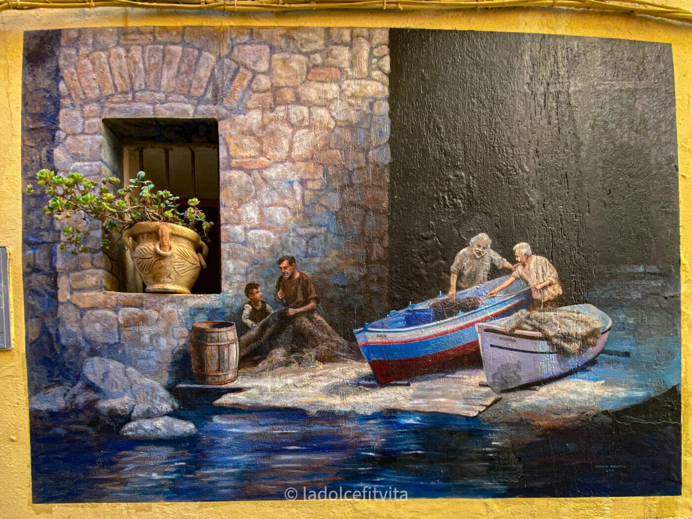 a mural of fishermen moving a boat painted in the town of diamante in calabria southern italy