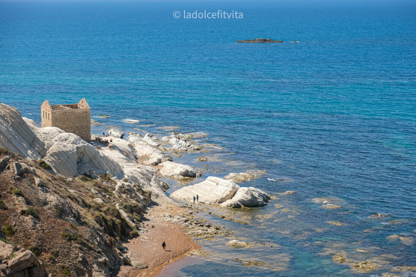 A building in ruins standing on a white calcareous cliffside on the shores of Punta Bianca beach in Agrigento, Sicily