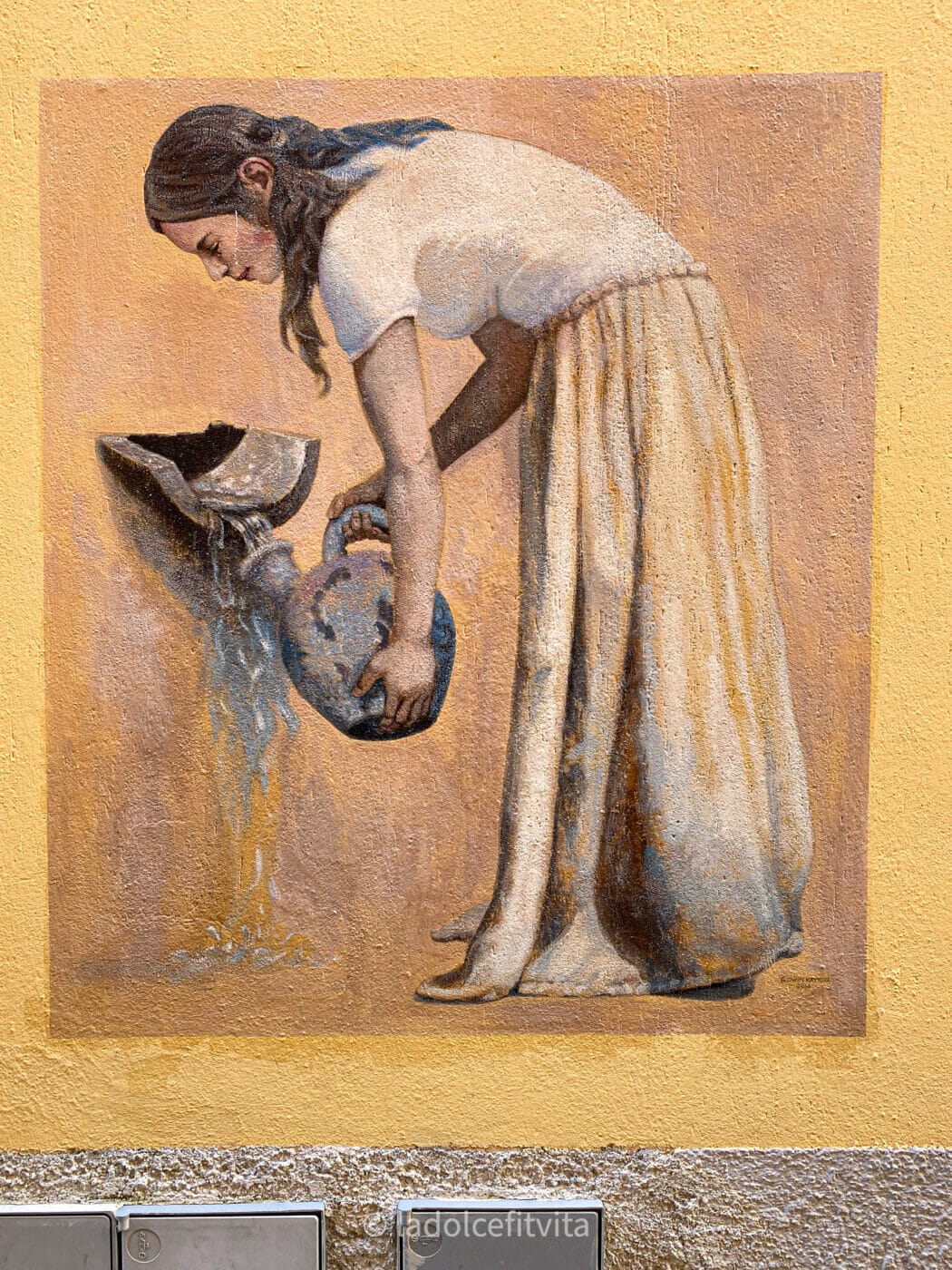 a mural painted in the Italian town of Diamante of a lady gathering water