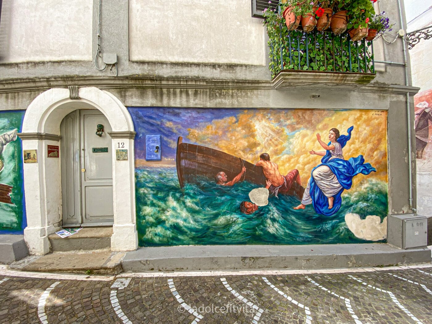 a mural of a shipwreck painted beside a doorway in the town of Diamante Italy