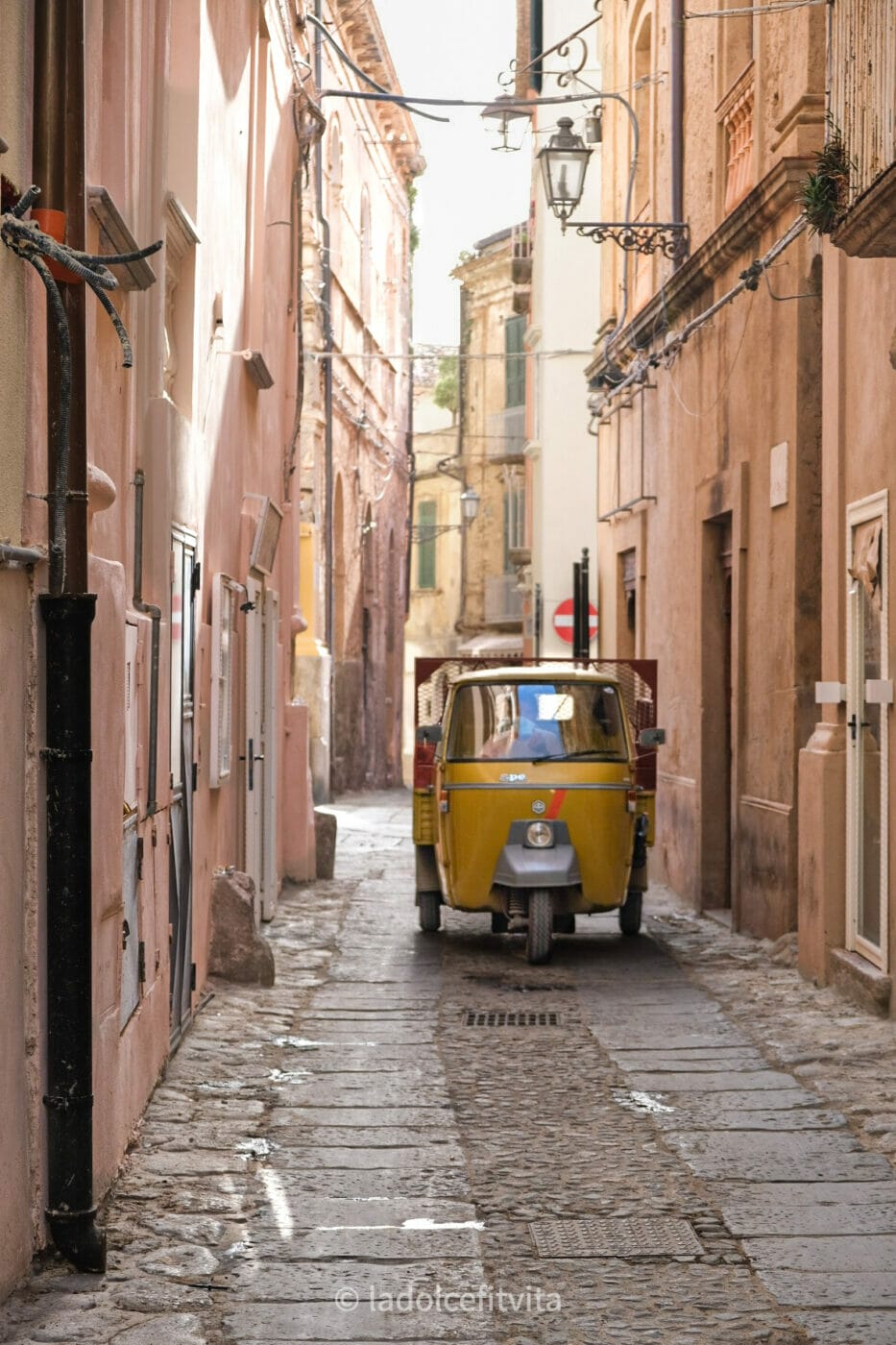a yellow ape-car driving in the narrow alleys of Calabrian seaside town of Tropea